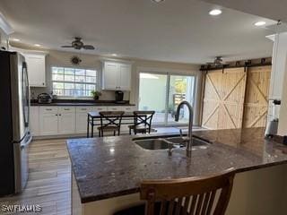 kitchen featuring white cabinets, a barn door, and stainless steel refrigerator