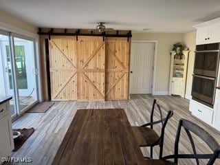 15700 Bahama Way, Bokeelia, FL 33922 - unfurnished living room featuring wood finished floors, a barn door, and baseboards