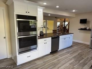 kitchen featuring sink, black dishwasher, double oven, light hardwood / wood-style floors, and white cabinetry