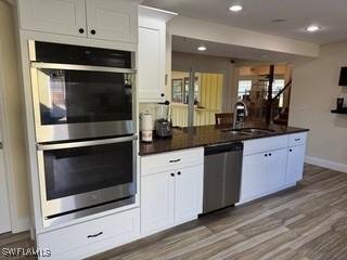 kitchen featuring white cabinets, light hardwood / wood-style floors, sink, and appliances with stainless steel finishes