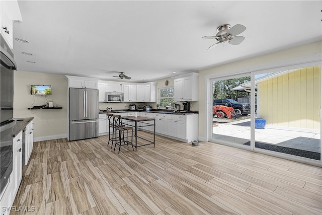 15700 Bahama Way, Bokeelia, FL 33922 - kitchen featuring ceiling fan, appliances with stainless steel finishes, dark countertops, light wood-type flooring, and white cabinets