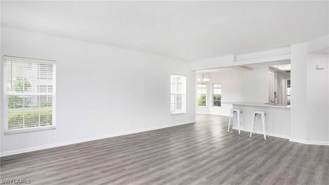 unfurnished living room featuring a notable chandelier and hardwood / wood-style floors