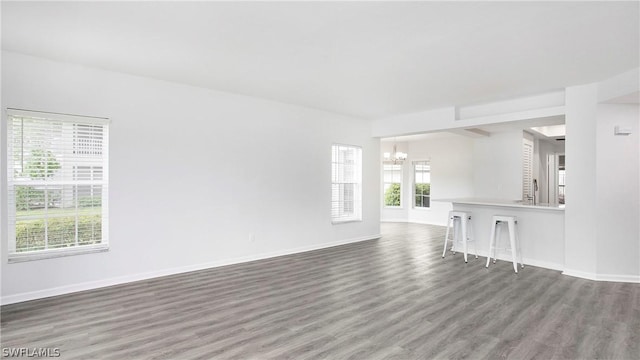 empty room with dark wood-type flooring and an inviting chandelier