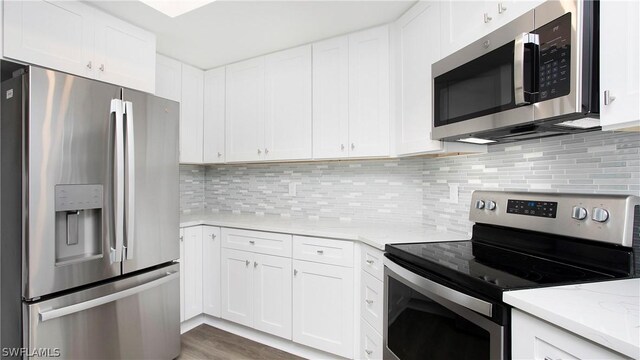 kitchen with light stone countertops, decorative backsplash, stainless steel appliances, and white cabinets