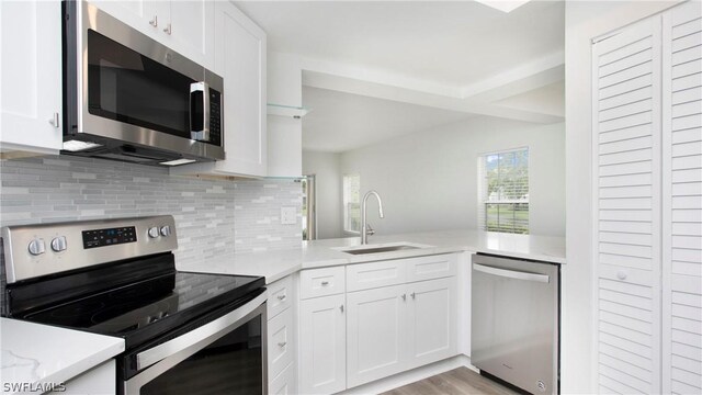 kitchen with sink, appliances with stainless steel finishes, light wood-type flooring, and white cabinetry