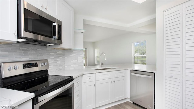 kitchen featuring sink, appliances with stainless steel finishes, white cabinets, decorative backsplash, and kitchen peninsula