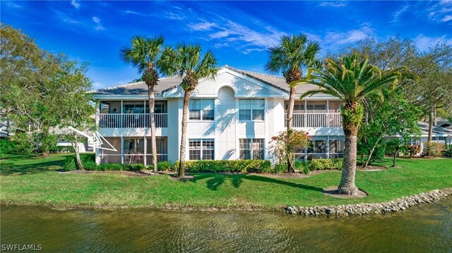 back of house with a yard, a water view, and a balcony