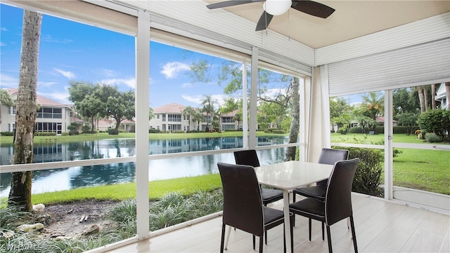 sunroom / solarium featuring a water view and ceiling fan