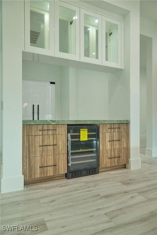 bar with baseboards, wine cooler, and light wood-style floors