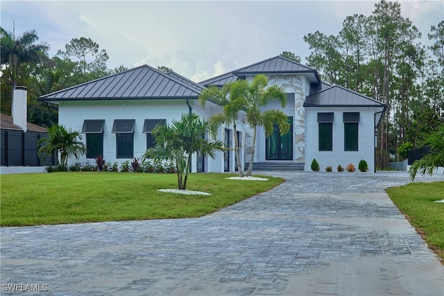 contemporary house featuring a standing seam roof, a front lawn, metal roof, and decorative driveway