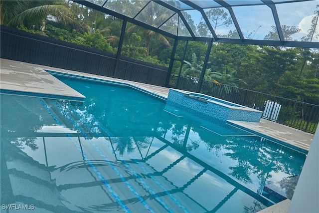 view of swimming pool featuring glass enclosure, a patio, fence, and a pool with connected hot tub