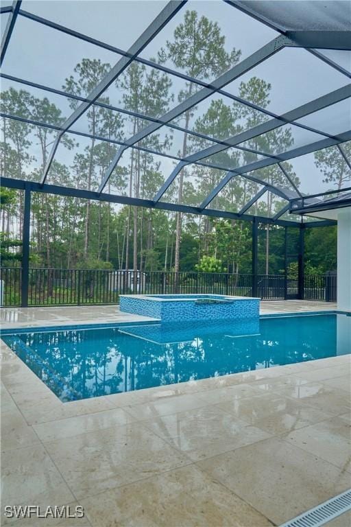 view of swimming pool with a pool with connected hot tub, glass enclosure, a patio, and fence