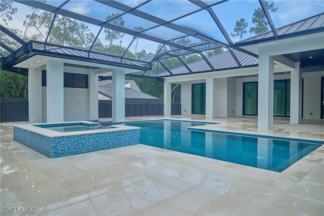 view of swimming pool featuring glass enclosure, a pool with connected hot tub, and a patio