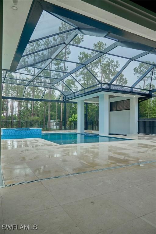 pool featuring glass enclosure, a patio area, and fence