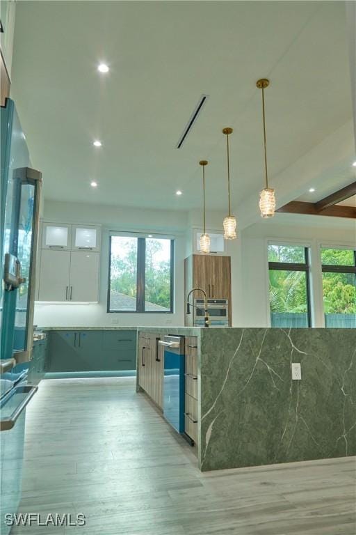 kitchen with white cabinets, glass insert cabinets, light wood-type flooring, stone counters, and pendant lighting