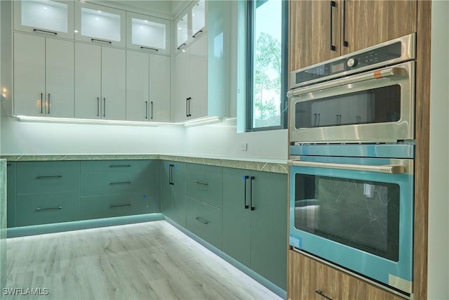 kitchen with double oven, light countertops, and glass insert cabinets