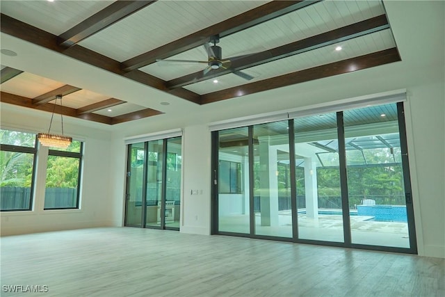 spare room with ceiling fan, a sunroom, wood finished floors, and beam ceiling