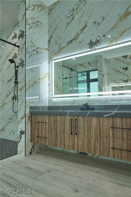 bathroom featuring vanity and a marble finish shower