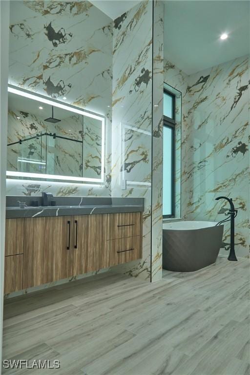 full bathroom featuring double vanity, a soaking tub, a shower, and wood finished floors