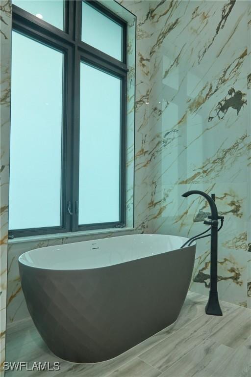 bathroom featuring a freestanding bath and tile walls