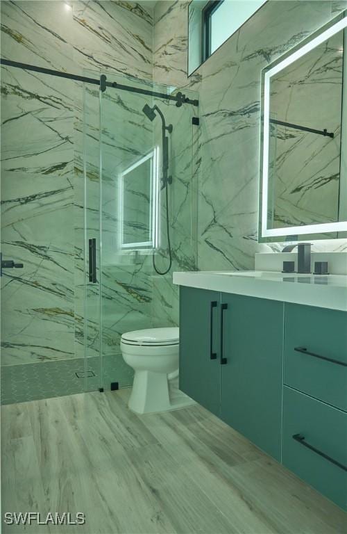 bathroom featuring toilet, a marble finish shower, and vanity