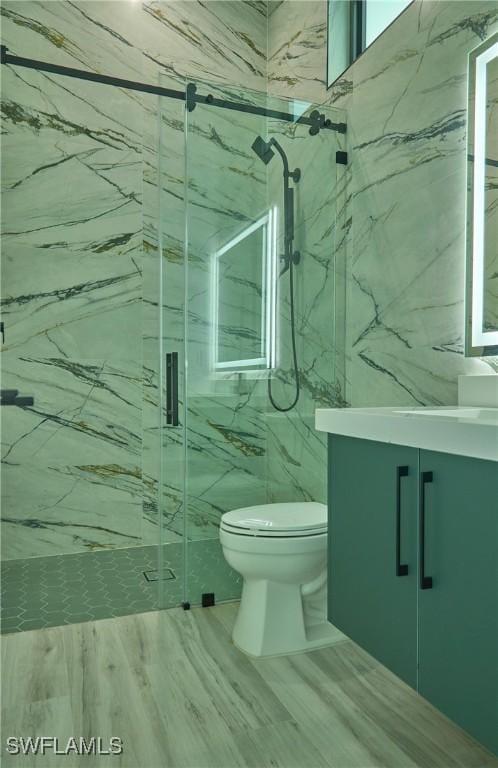 full bath featuring tile walls, a marble finish shower, toilet, vanity, and wood finished floors