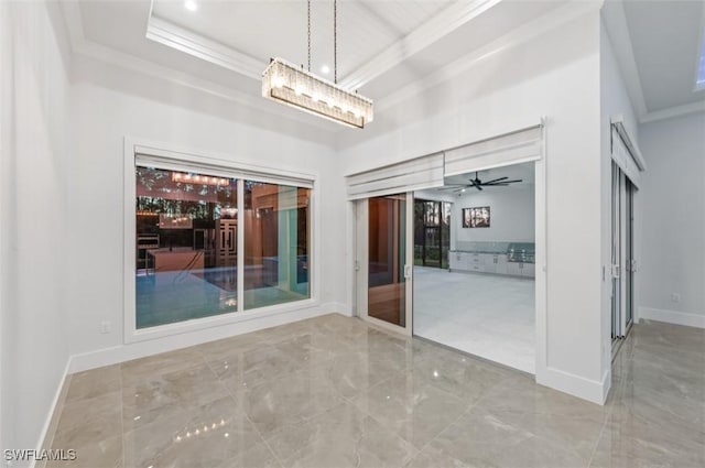 empty room featuring a raised ceiling, ceiling fan, and ornamental molding