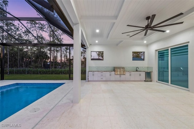 pool at dusk with ceiling fan, area for grilling, and sink