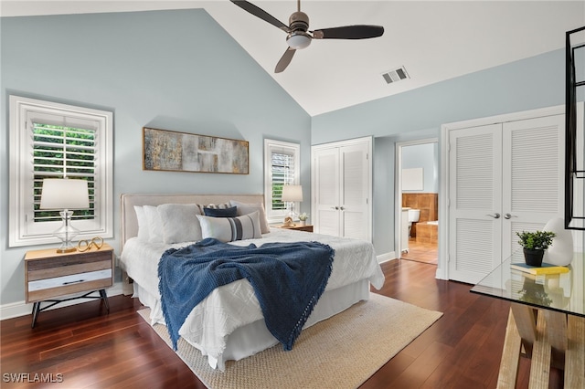 bedroom with two closets, high vaulted ceiling, dark hardwood / wood-style floors, and ceiling fan