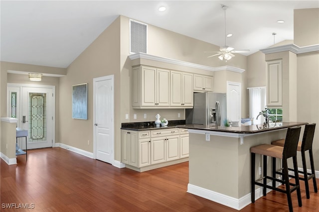 kitchen featuring wood-type flooring, a breakfast bar, kitchen peninsula, and stainless steel refrigerator with ice dispenser