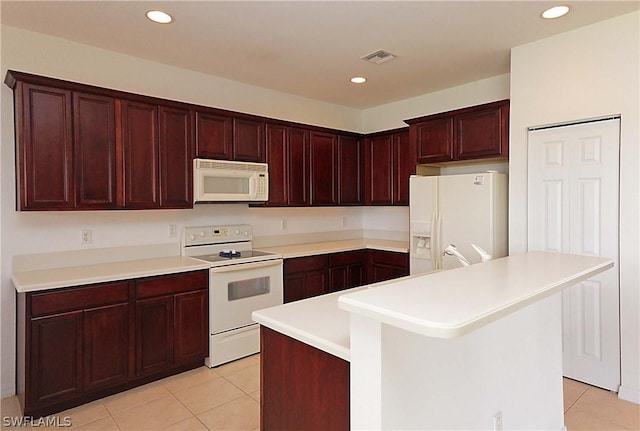 kitchen featuring white appliances, a kitchen breakfast bar, a center island, and light tile patterned floors