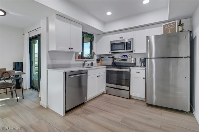 kitchen featuring appliances with stainless steel finishes, light hardwood / wood-style flooring, white cabinets, and sink