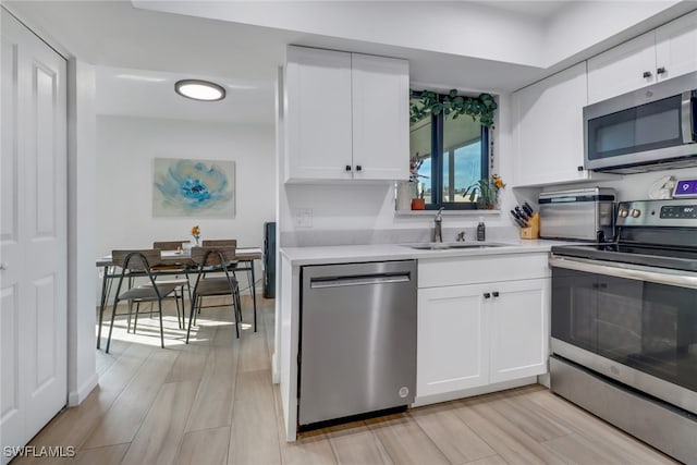 kitchen with white cabinets, stainless steel appliances, light hardwood / wood-style floors, and sink