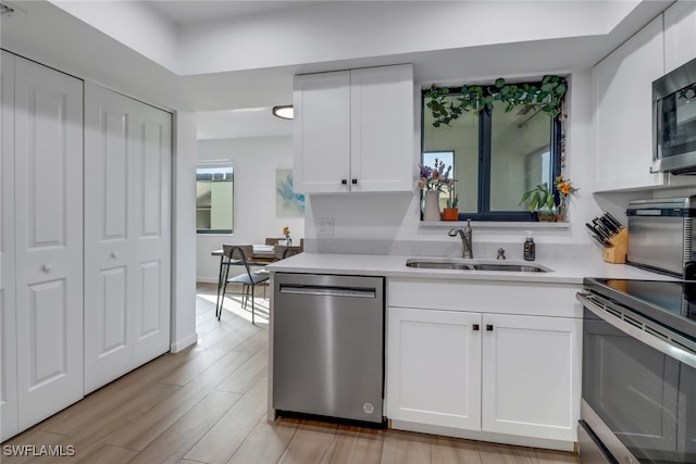 kitchen featuring sink, light wood-type flooring, stainless steel appliances, and white cabinets