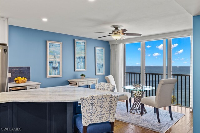 kitchen with a water view, light stone countertops, ceiling fan, dark wood-type flooring, and white cabinets