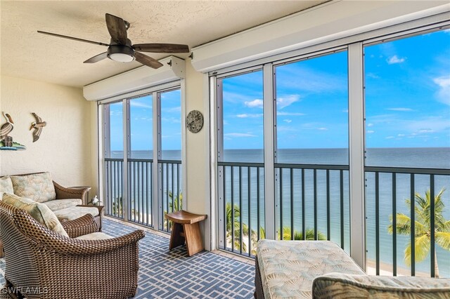 sunroom / solarium featuring ceiling fan and a water view