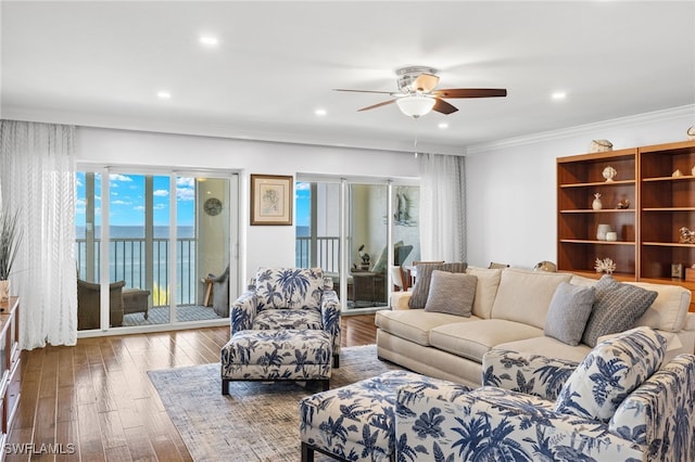 living room featuring ceiling fan, a water view, wood-type flooring, and crown molding