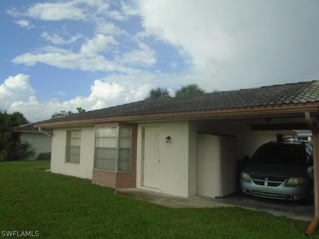 exterior space with a tiled roof, an attached carport, a front yard, and stucco siding