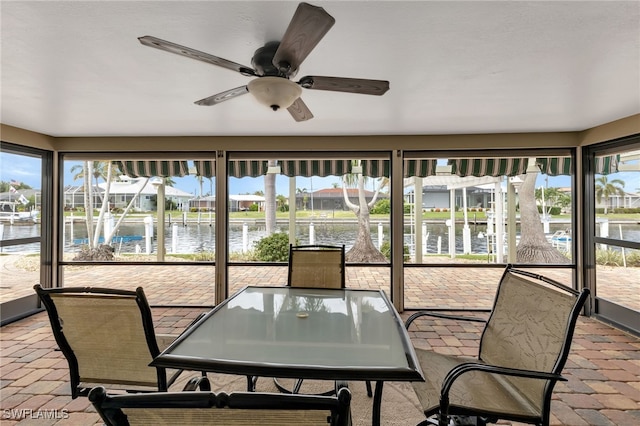 sunroom / solarium with ceiling fan, a wealth of natural light, and a water view