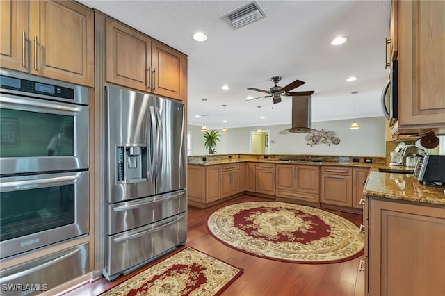 kitchen featuring appliances with stainless steel finishes, light wood-type flooring, kitchen peninsula, and wall chimney exhaust hood