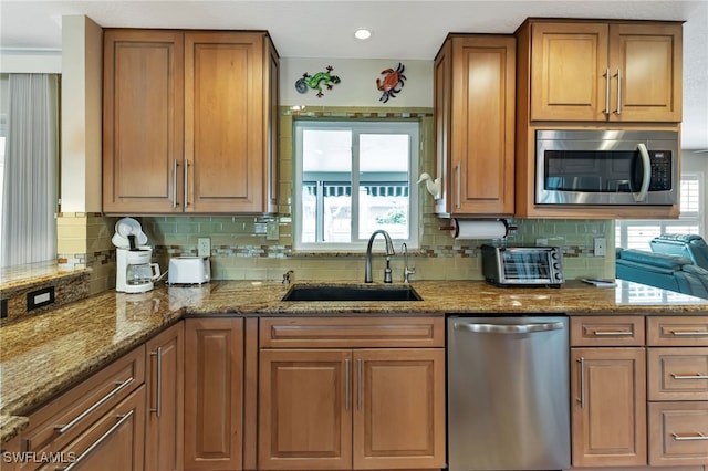 kitchen with sink, stainless steel appliances, stone countertops, and decorative backsplash