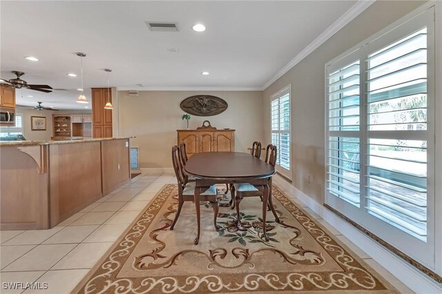 dining room with ceiling fan, ornamental molding, and light tile patterned floors