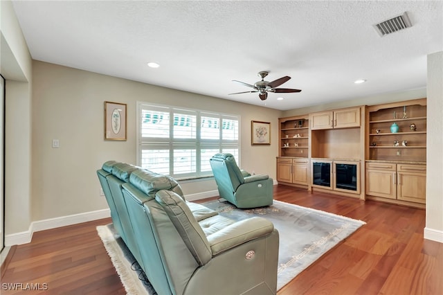 living room featuring ceiling fan, a textured ceiling, and wood-type flooring