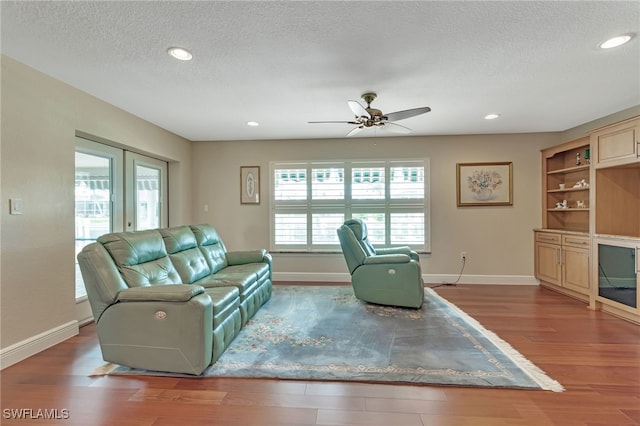 living room with a textured ceiling, wood-type flooring, and ceiling fan