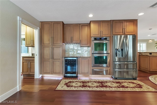 kitchen with appliances with stainless steel finishes, a textured ceiling, dark hardwood / wood-style floors, and wine cooler