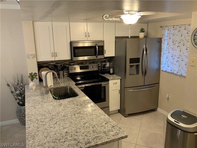 kitchen with appliances with stainless steel finishes, tasteful backsplash, white cabinets, light stone countertops, and ceiling fan