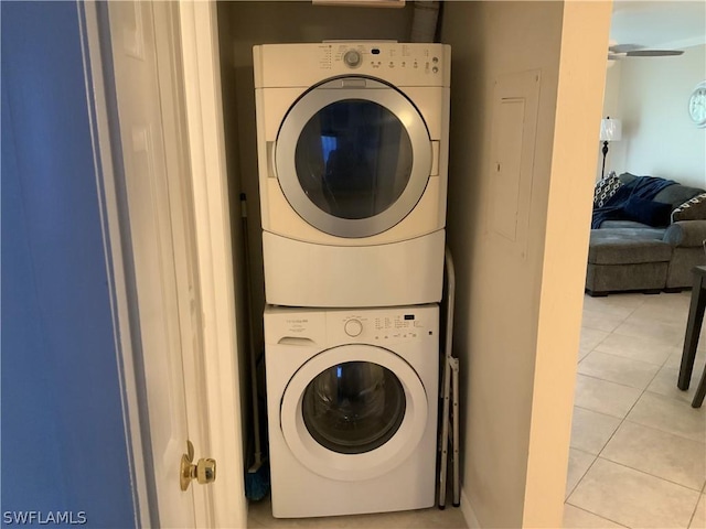 laundry area featuring light tile patterned flooring and stacked washer and clothes dryer