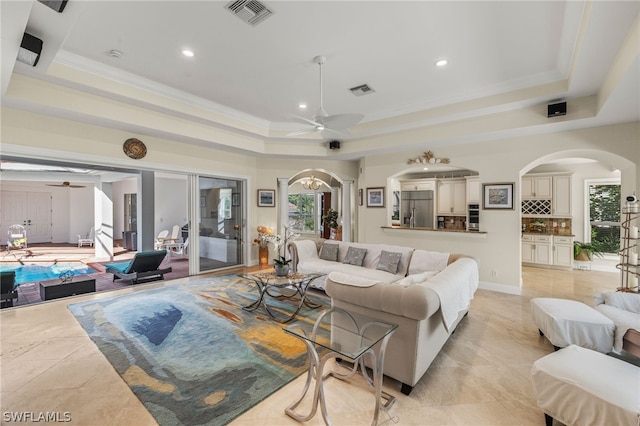 living room featuring crown molding, a tray ceiling, and ceiling fan