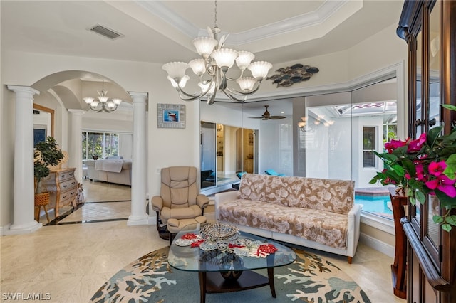 living room featuring a raised ceiling, ornamental molding, ceiling fan with notable chandelier, and ornate columns