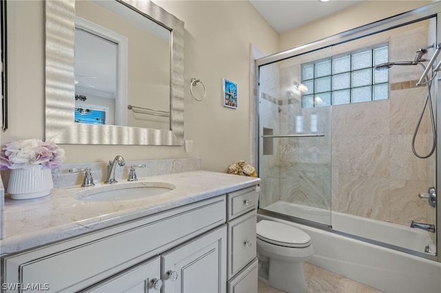 full bathroom featuring vanity, shower / bath combination with glass door, and toilet